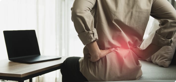 Person experiencing severe lower back pain while sitting