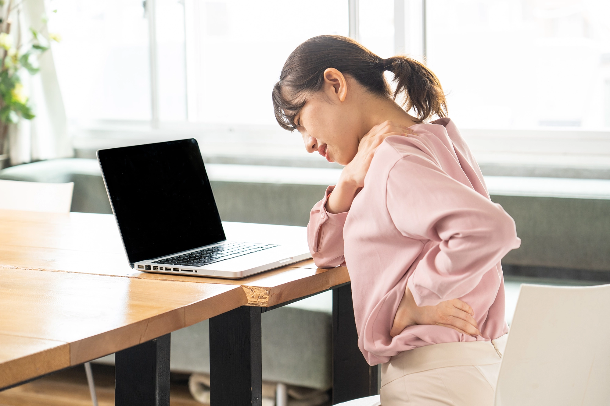 Asian woman at her desk suffering pain in the lower back