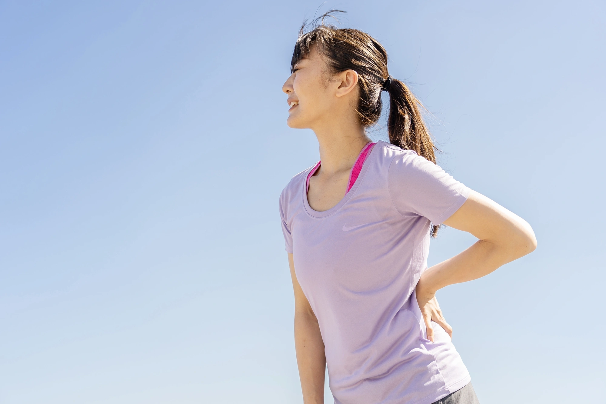 sporty asian woman holding her hip outside