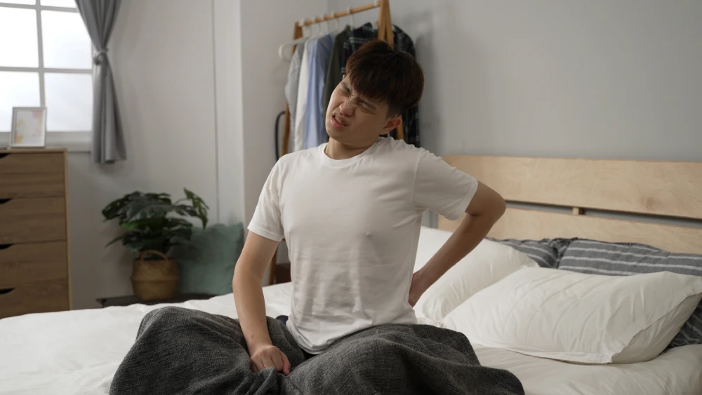 Man holding his lower back and showing signs of discomfort.