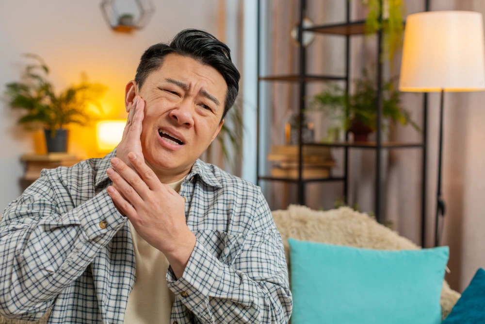 Man touching one side of his face in pain.