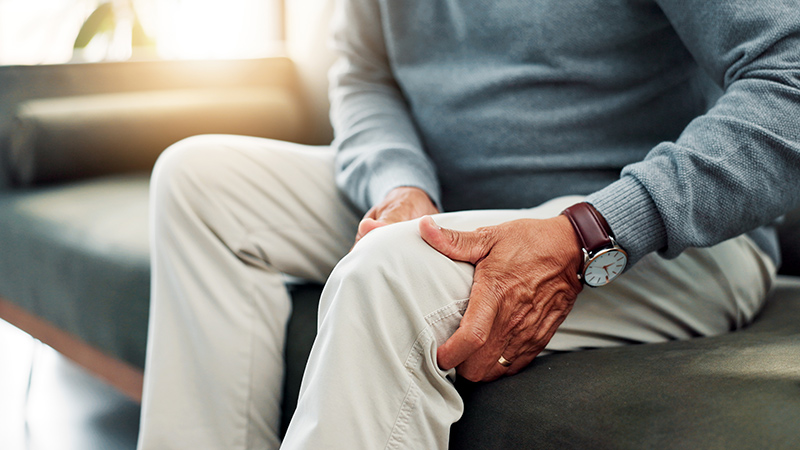 Man holding his knee, indicating leg discomfort or injury.