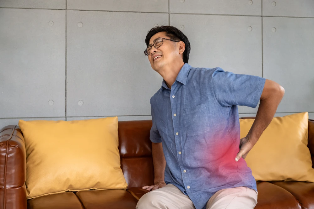 Man experiencing sharp lower back pain while sitting.