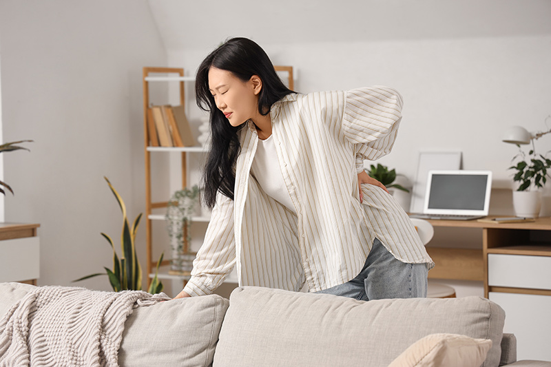 Woman holding on to her lower back, experiencing back pain and discomfort.