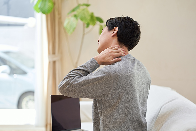 Man holding his neck in visible pain, illustrating neck pain or soreness.