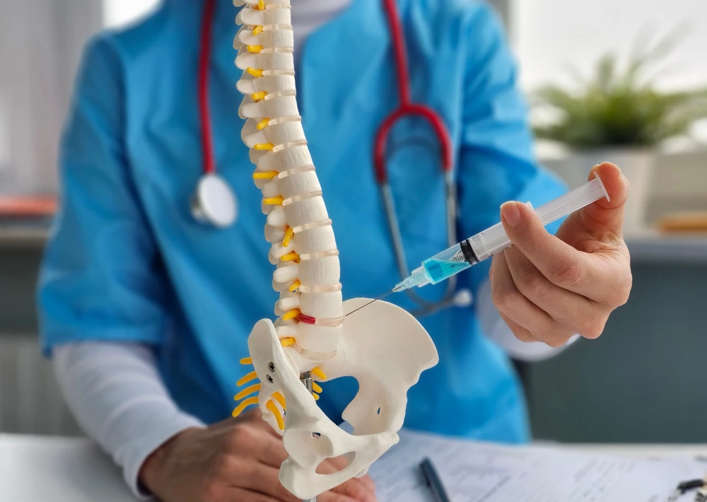 Office worker sitting at a desk and holding their lower back in discomfort, illustrating work‑related back pain.