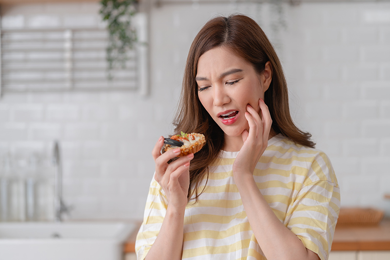 Woman experiencing sharp facial pain while eating.