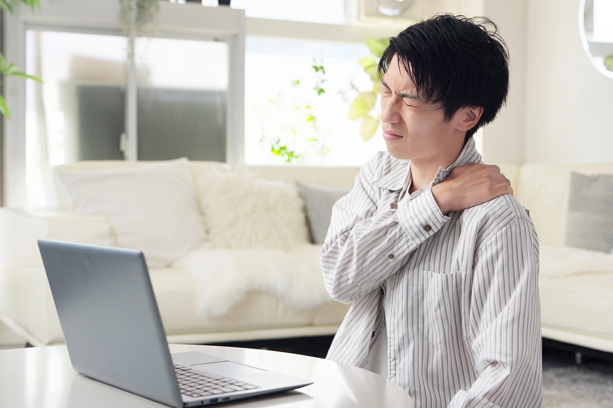 Man holding his shoulder with a pained expression, illustrating chronic shoulder pain and ongoing discomfort.
