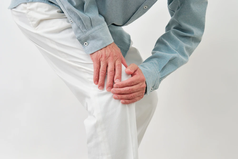 Man holding his leg and experiencing pain while standing.