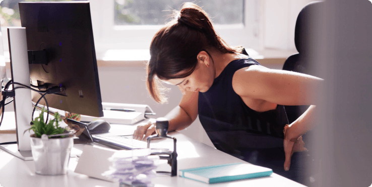 Person demonstrating poor posture at desk, a common risk factor for neck pain
